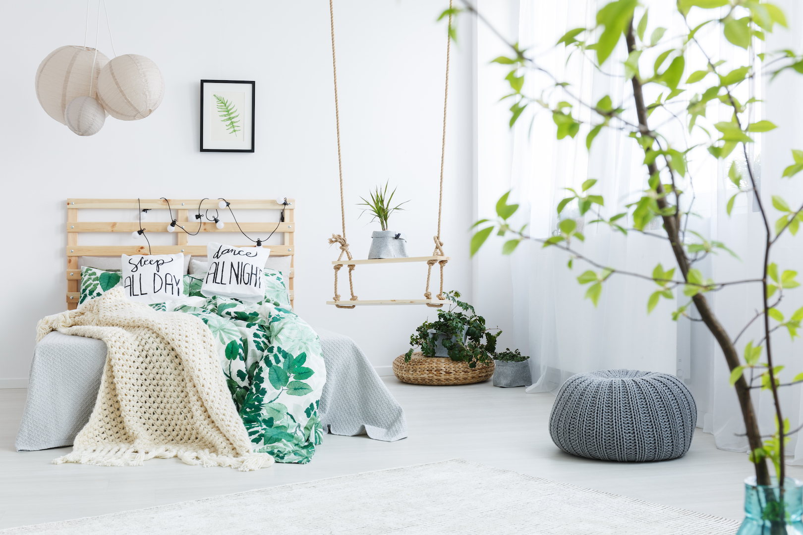 Bedroom with gray pouf, plants, double bed, lamp and swing